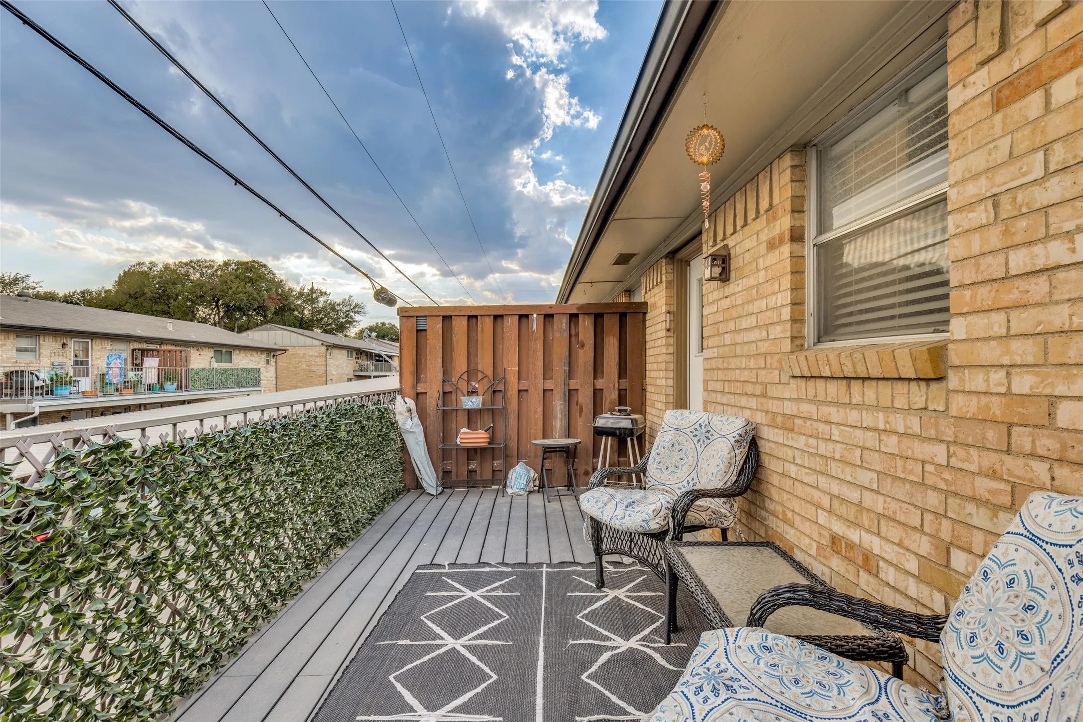 Outdoor balcony with composite decking, brick exterior wall, and a wood privacy fence