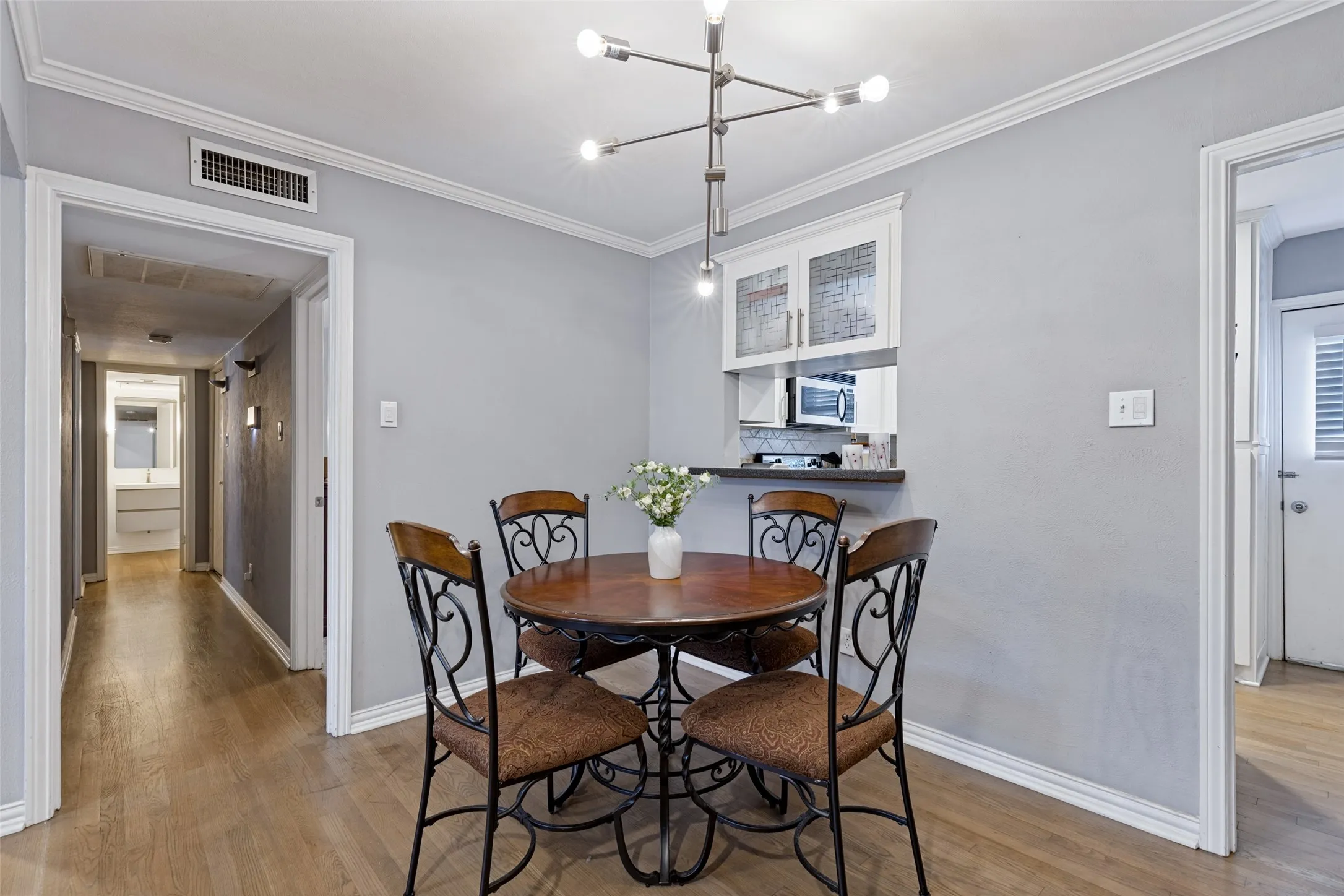 Wood-finish flooring with crown molding and a modern ceiling fixture