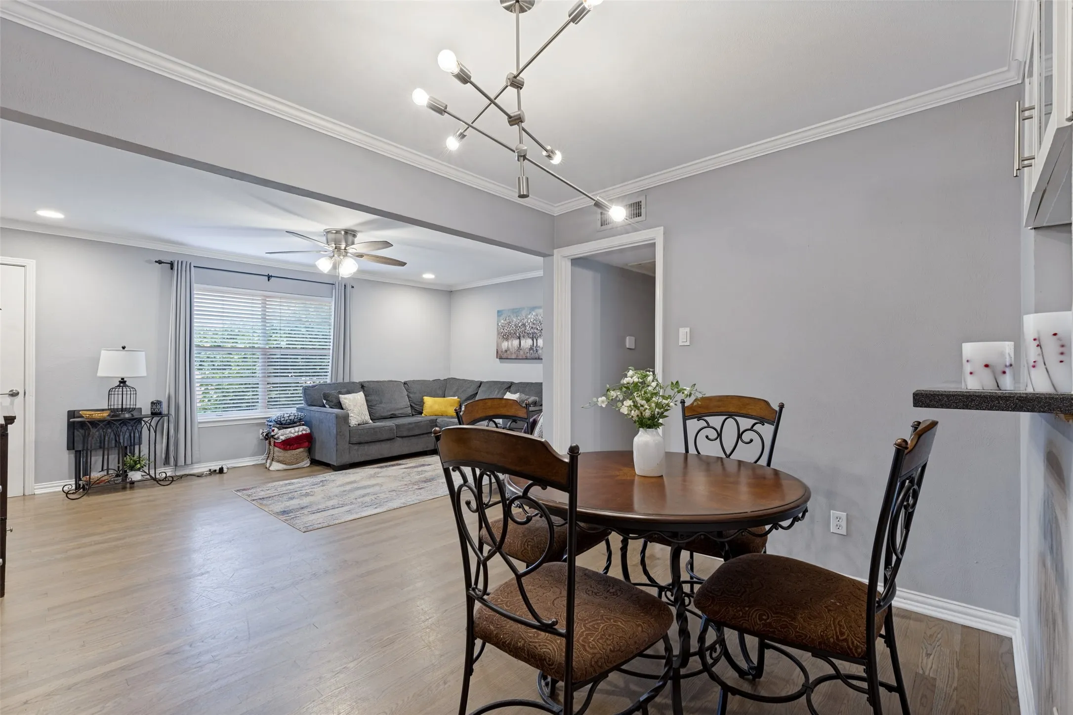 Wood-finish flooring, crown molding, recessed lighting, and a modern light fixture enhance the living area