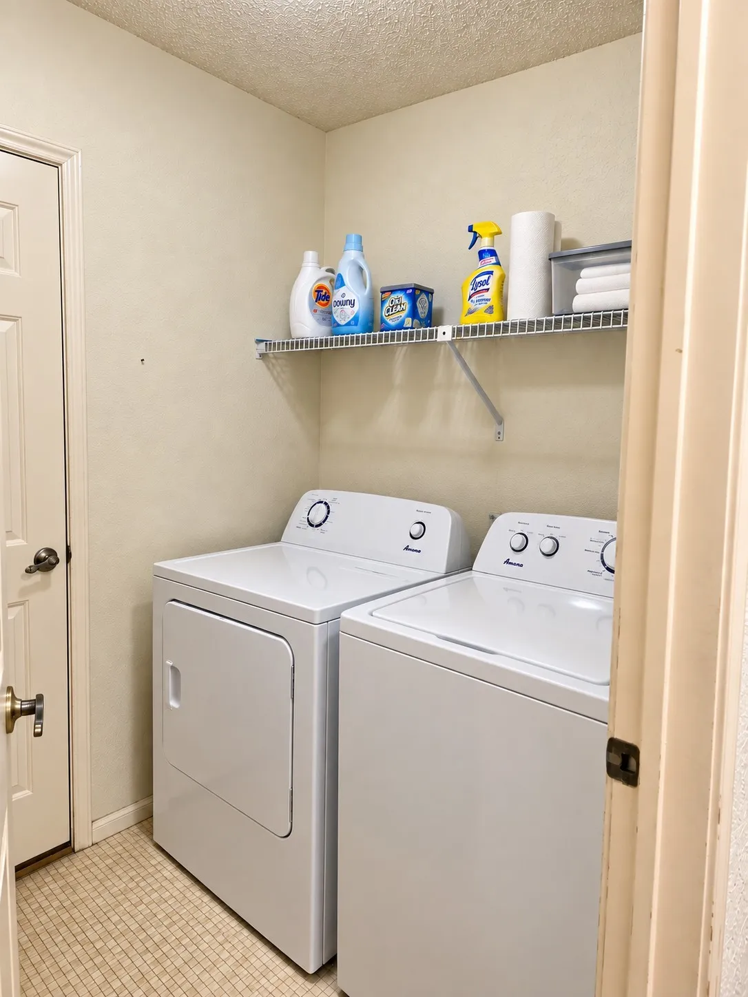 Laundry area featuring a wire storage shelf, white dryer, and white washing machine.  VIRTUALLY DECLUTTERED USING AI