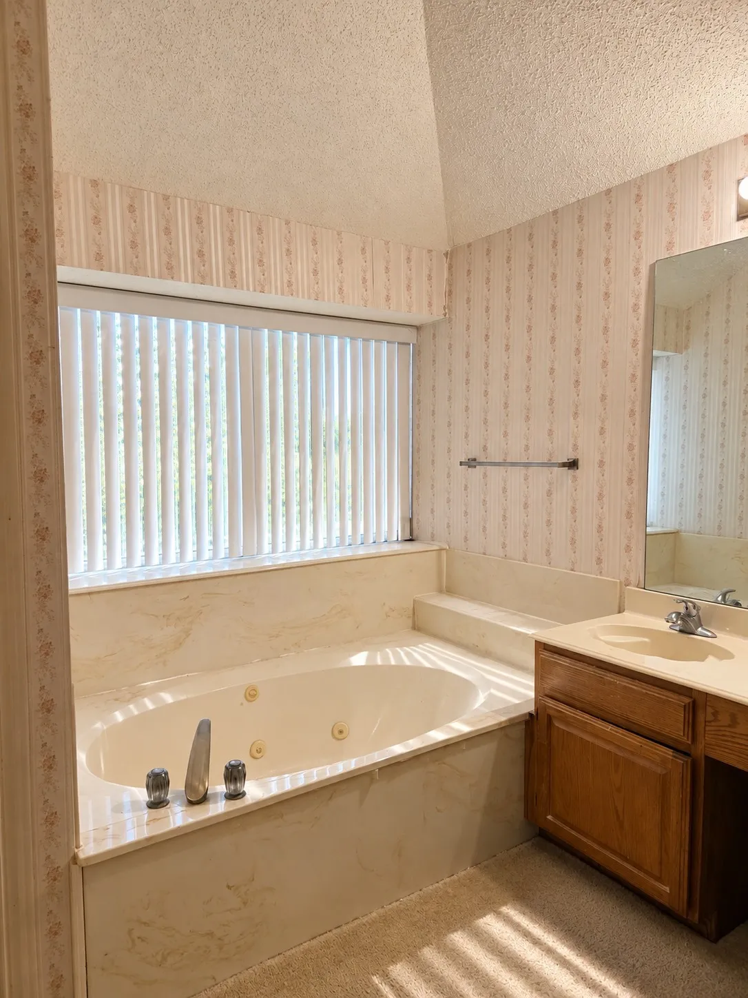 Built-in jetted tub with surround, vanity with an integrated sink, and an expansive mirror. VIRTUALLY DECLUTTERED USING AI