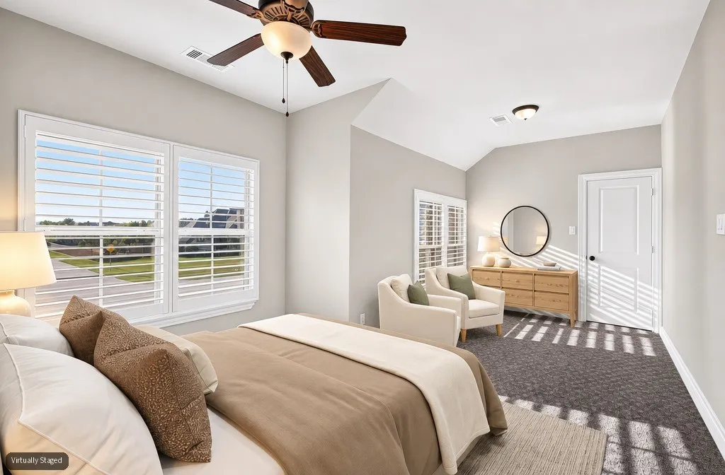 Vaulted ceiling, ceiling fan, white paneled door, shuttered windows, and textured carpet flooring
