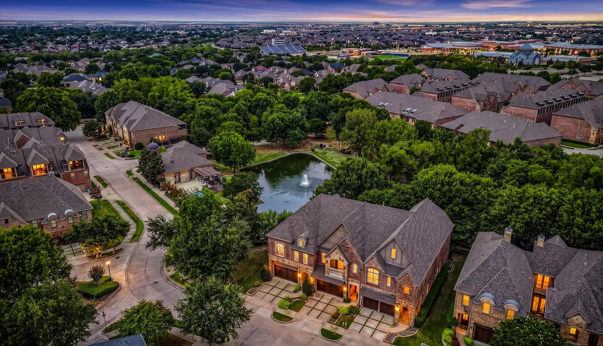 Residential neighborhood featuring a prominent pond with a water feature, mature trees, and varying architectural styles
