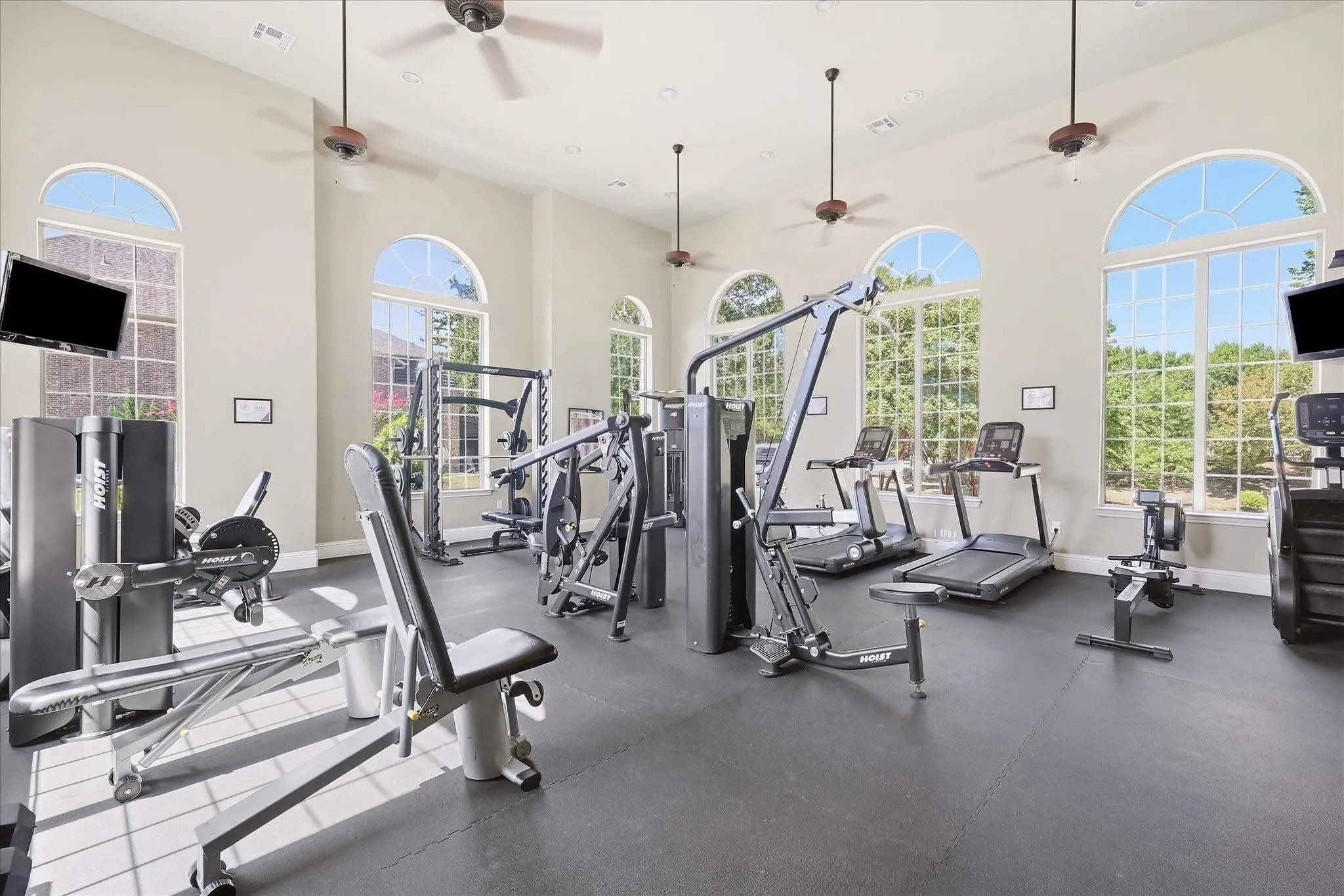 Fitness area with arched windows, high ceilings, ceiling fans, and rubber flooring