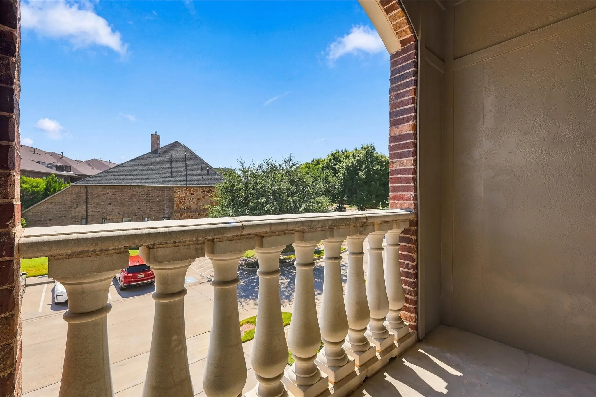 Balcony featuring a decorative balustrade, brick columns, and a textured exterior wall