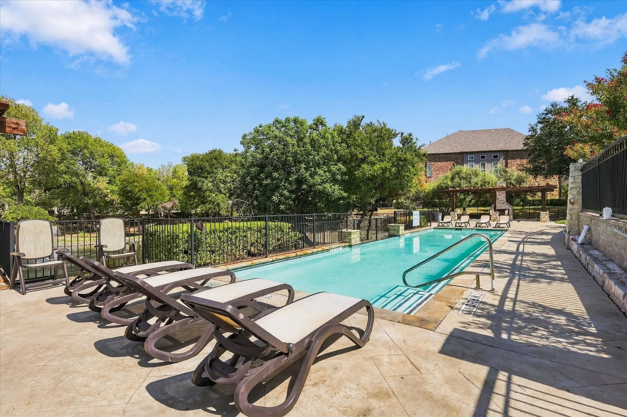 Rectangular swimming pool with integrated access rails, surrounded by a paved deck