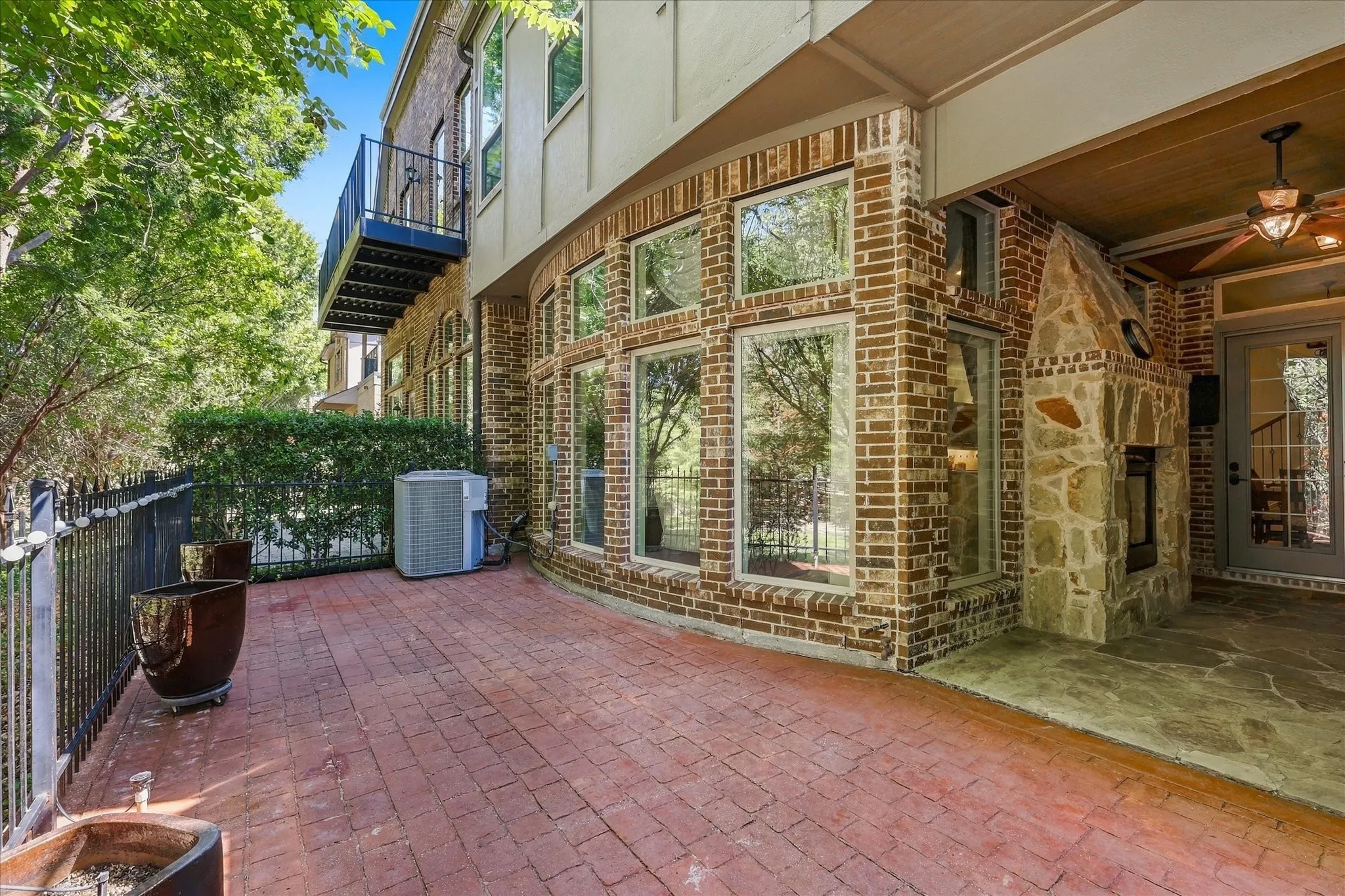Brick exterior with a stamped concrete patio, stone fireplace, and a second-story balcony