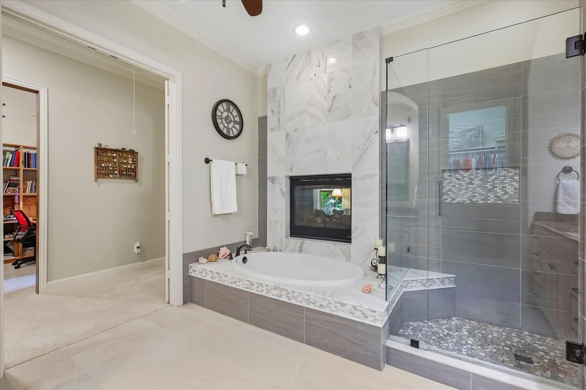 Soaking tub with a tiled surround, glass-enclosed shower, and a built-in fireplace feature