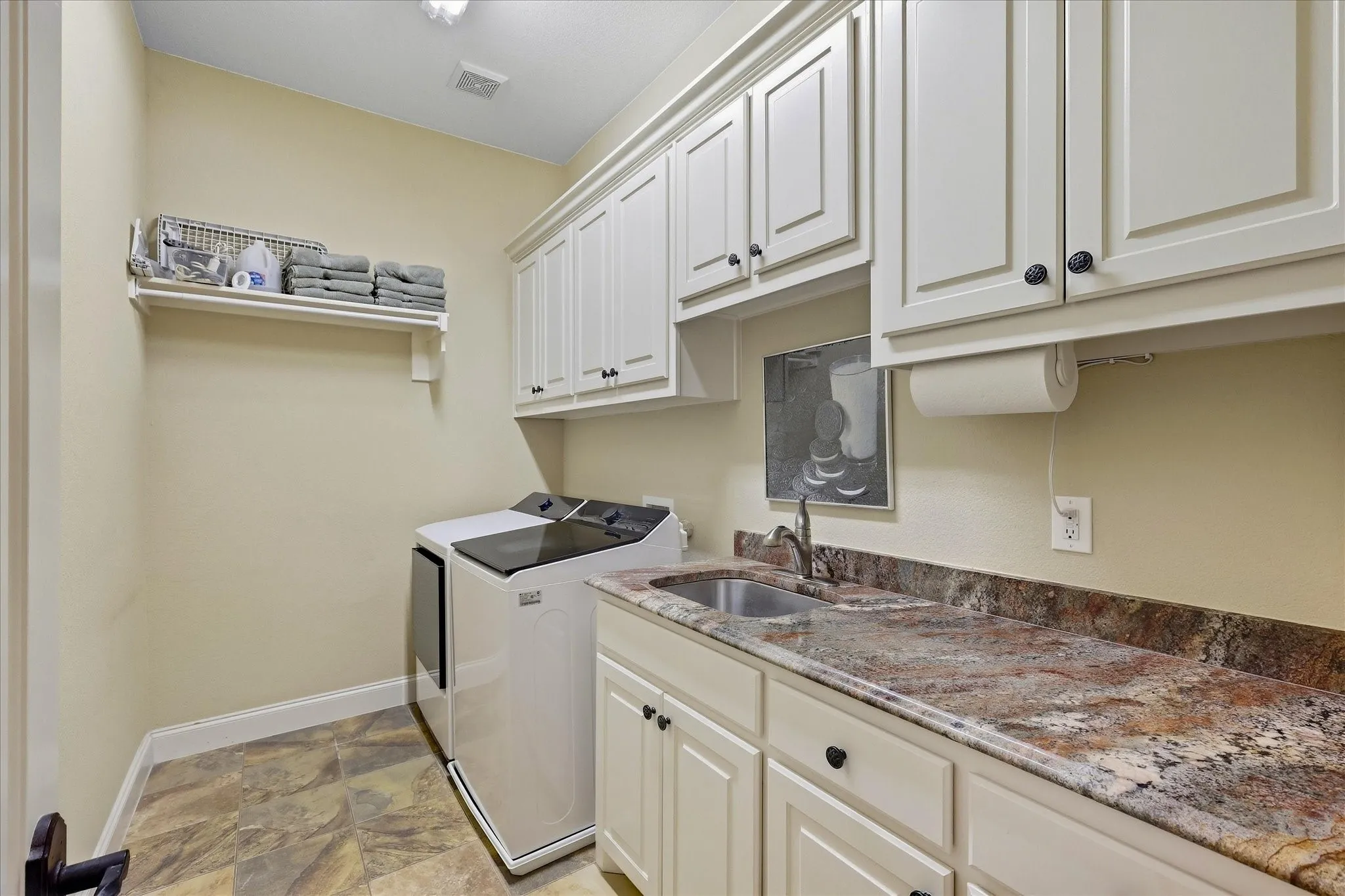 Laundry area featuring built-in cabinetry, a utility sink, and stone-finish countertops