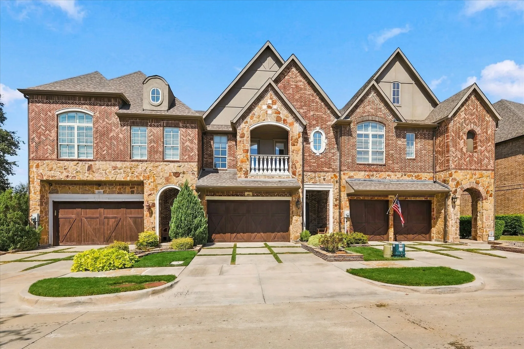 Brick and stone exterior featuring multiple gables, arched entryways, and dormer windows
