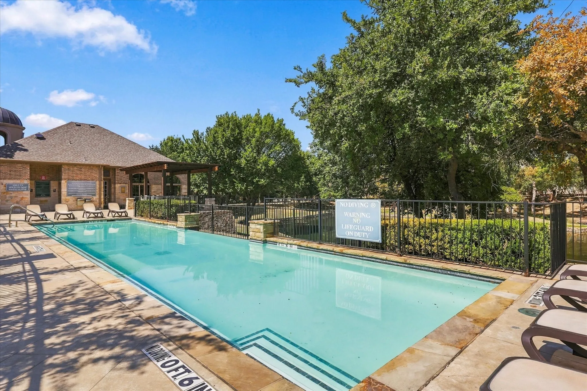 Rectangular swimming pool with integrated steps, surrounded by stone coping and a paved deck