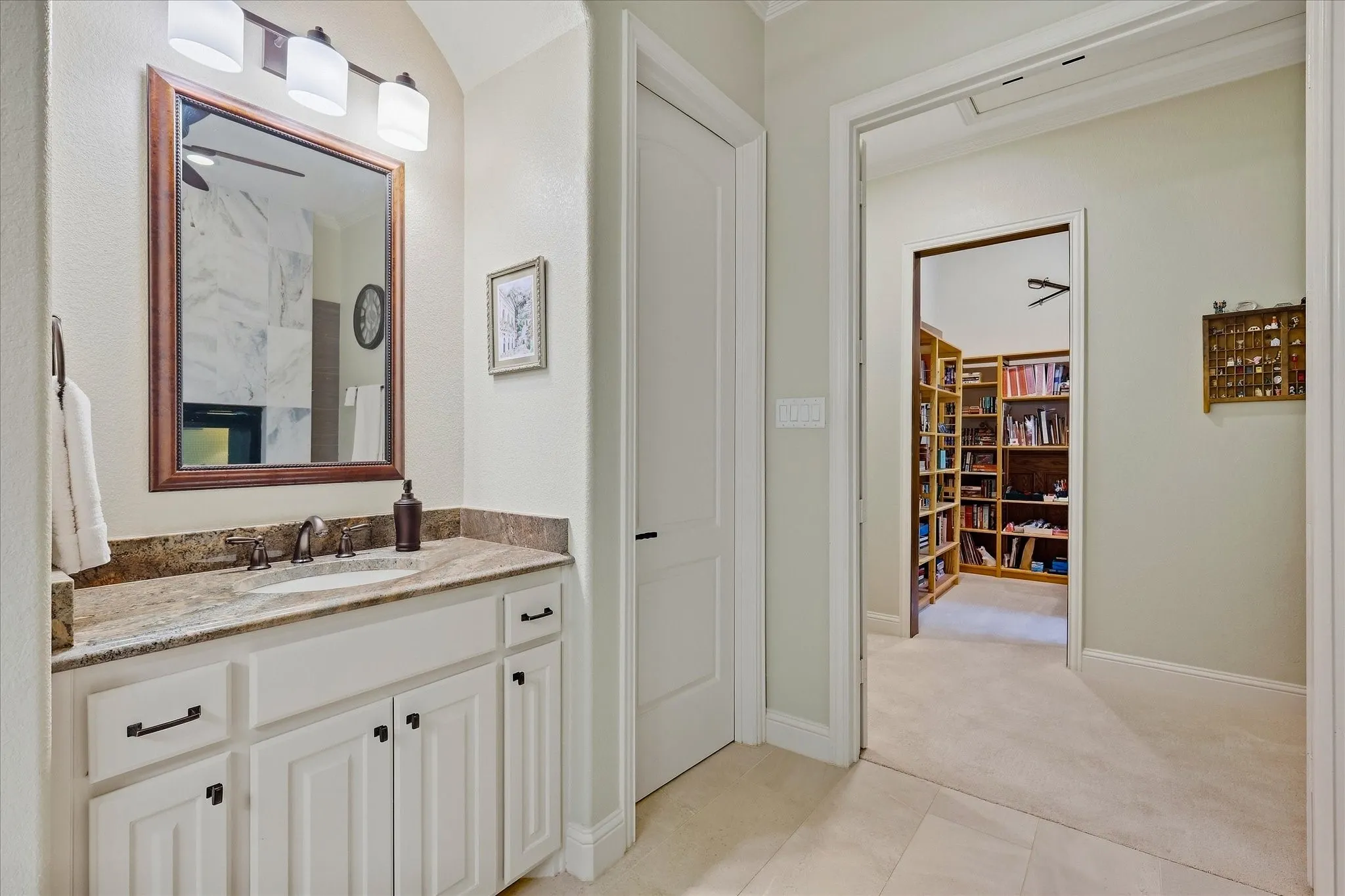 White vanity with dark hardware, stone countertop, and an undermount sink