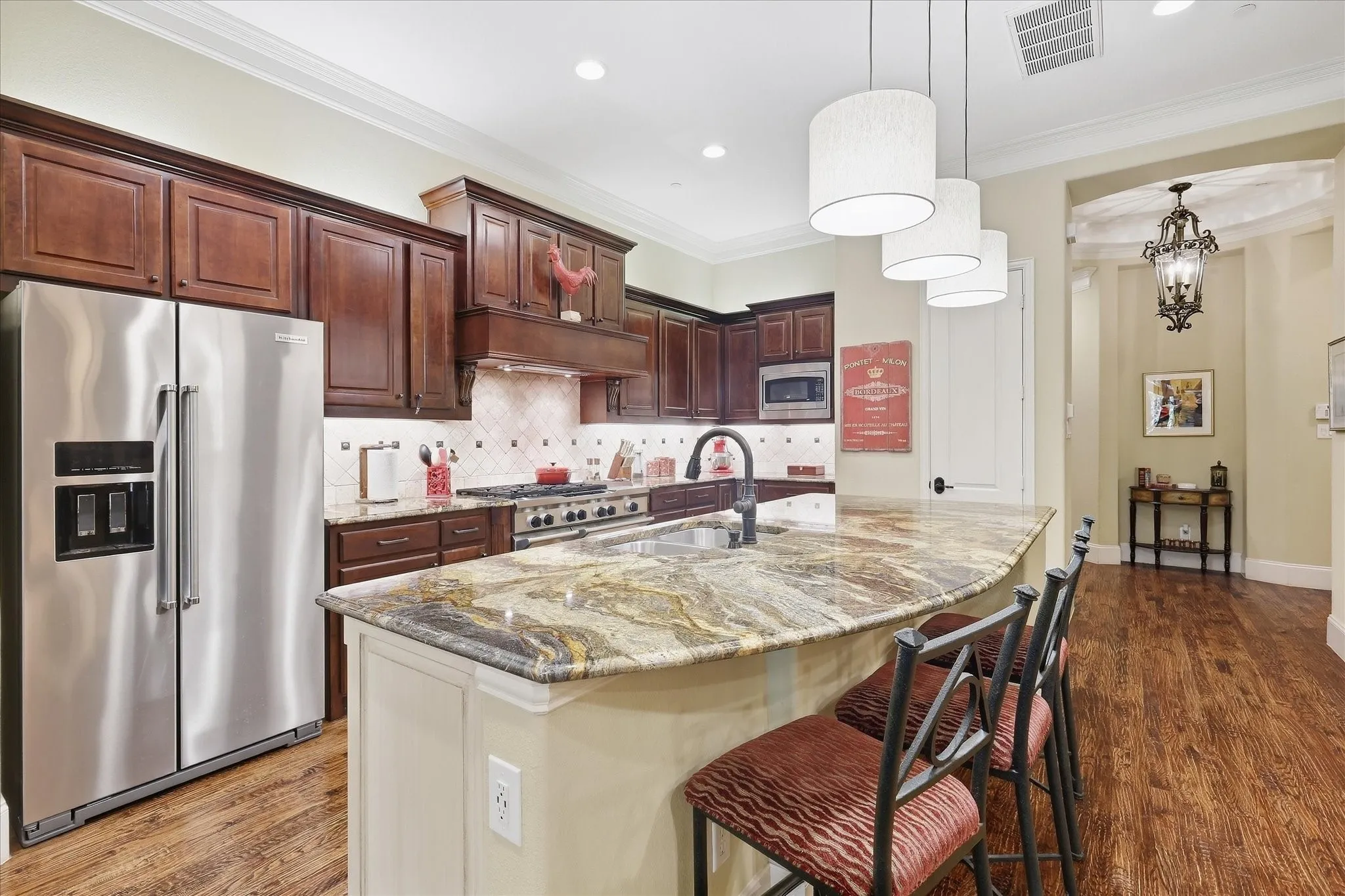 Kitchen featuring wood-finish flooring, dark wood cabinetry, stainless steel appliances, and a large island with a stone countertop
