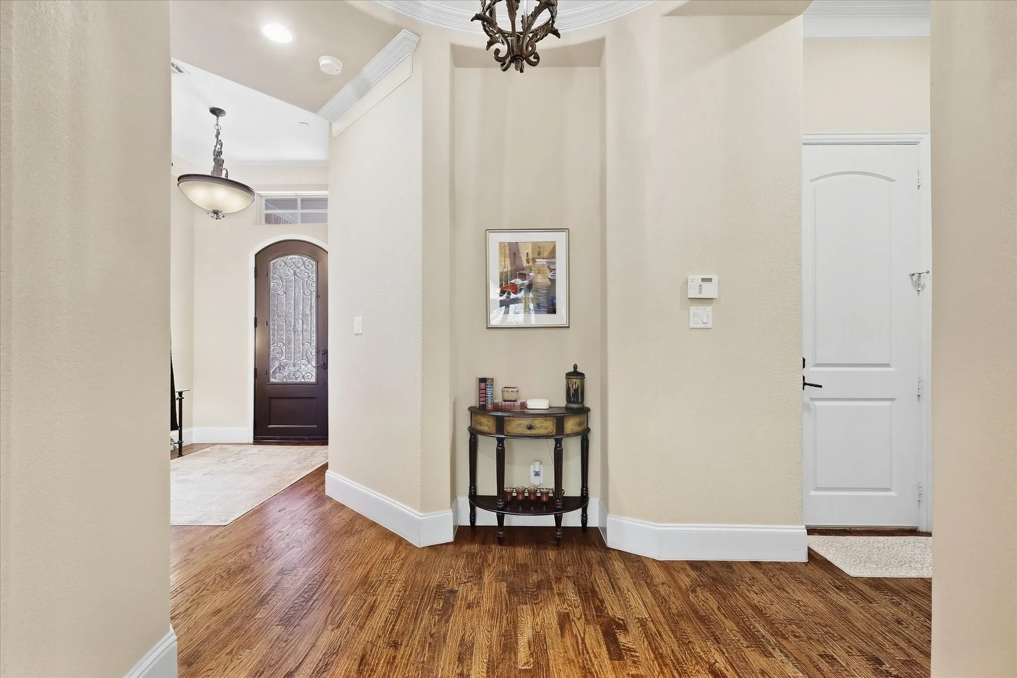 Hardwood flooring throughout, arched doorways, a coffered ceiling, and crown molding