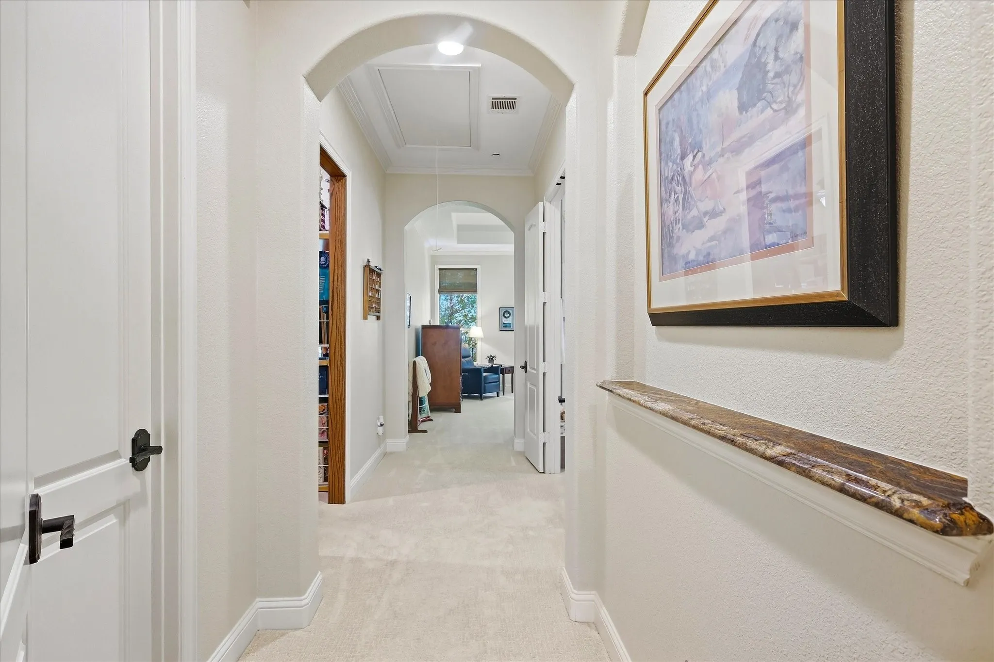 Arched doorways, carpeted flooring, and a wall-mounted picture ledge