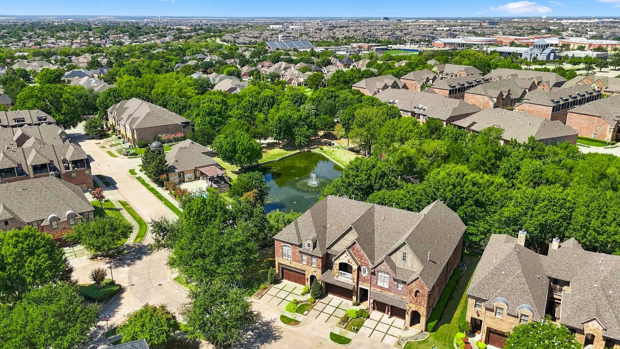 Expansive residential neighborhood featuring mature trees, landscaped streets, and a central pond with a water feature
