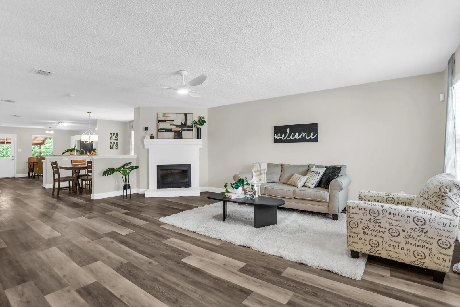 Wood-finish flooring, white ceiling fan, white fireplace, neutral wall paint, and recessed lighting