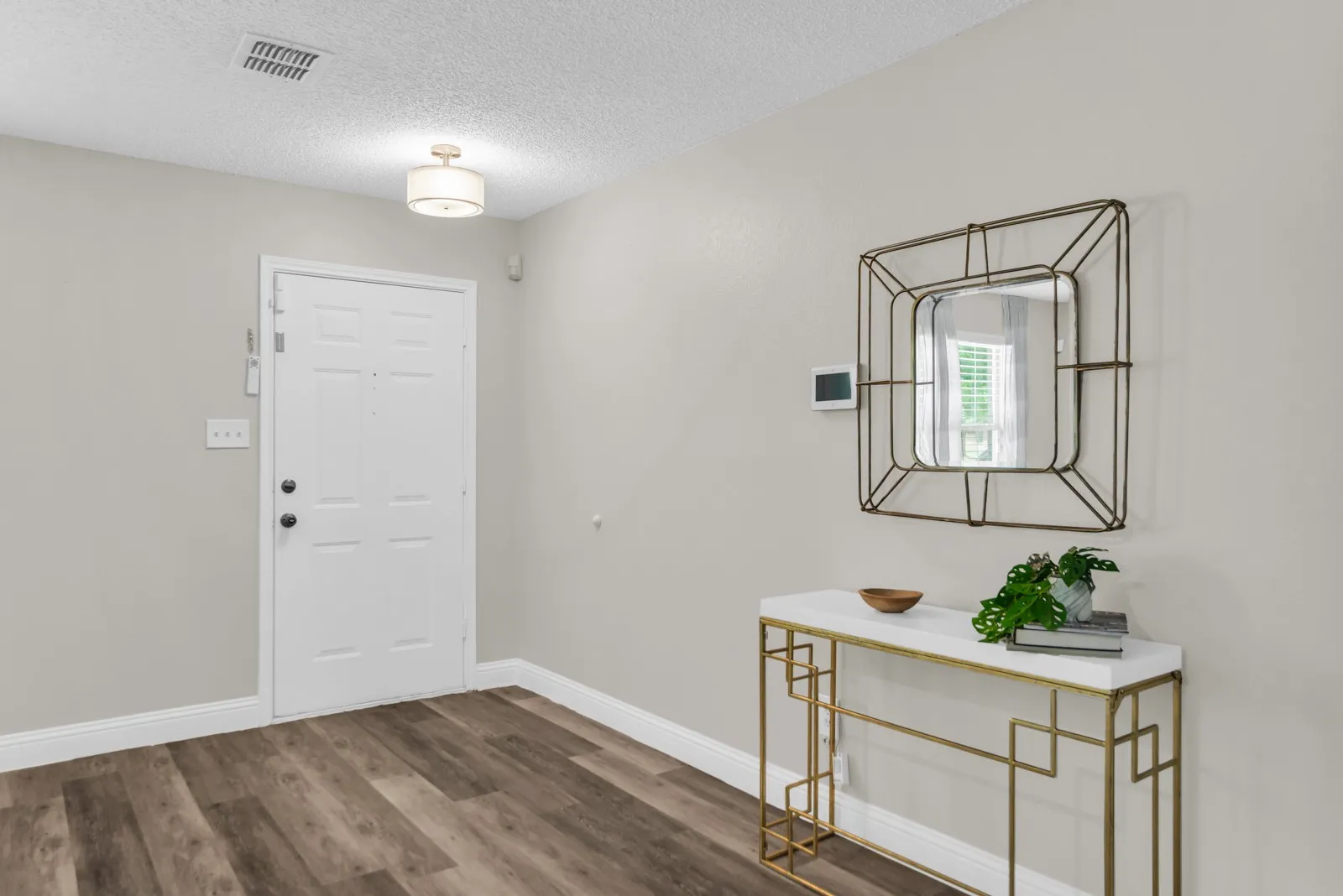 Wood-finish flooring, white paneled door, and a flush-mount ceiling light fixture