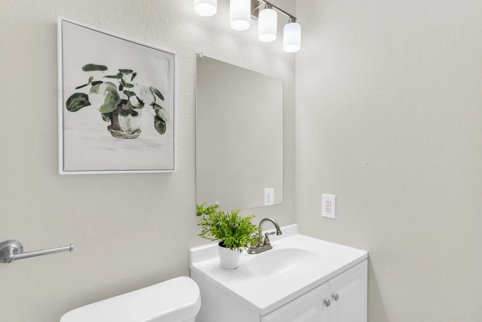 Vanity with an integrated sink, brushed nickel faucet, and a wall-mounted mirror