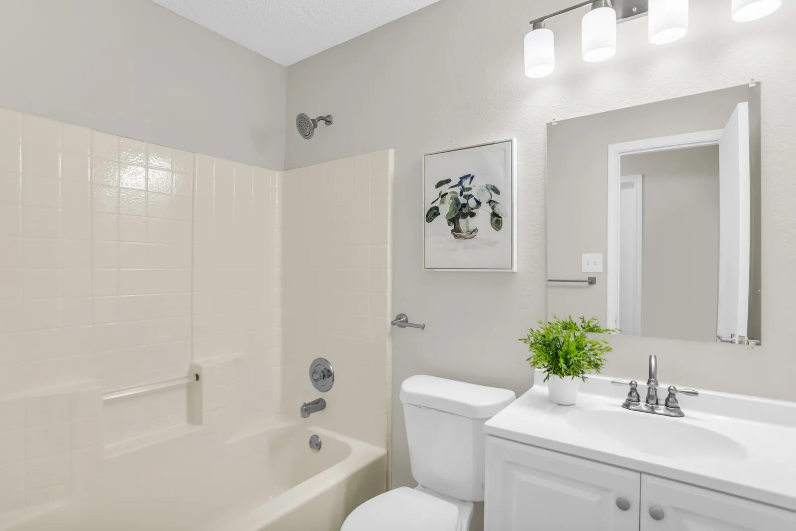 Enclosed bathtub with integrated tile surround, chrome shower head, and matching fixtures