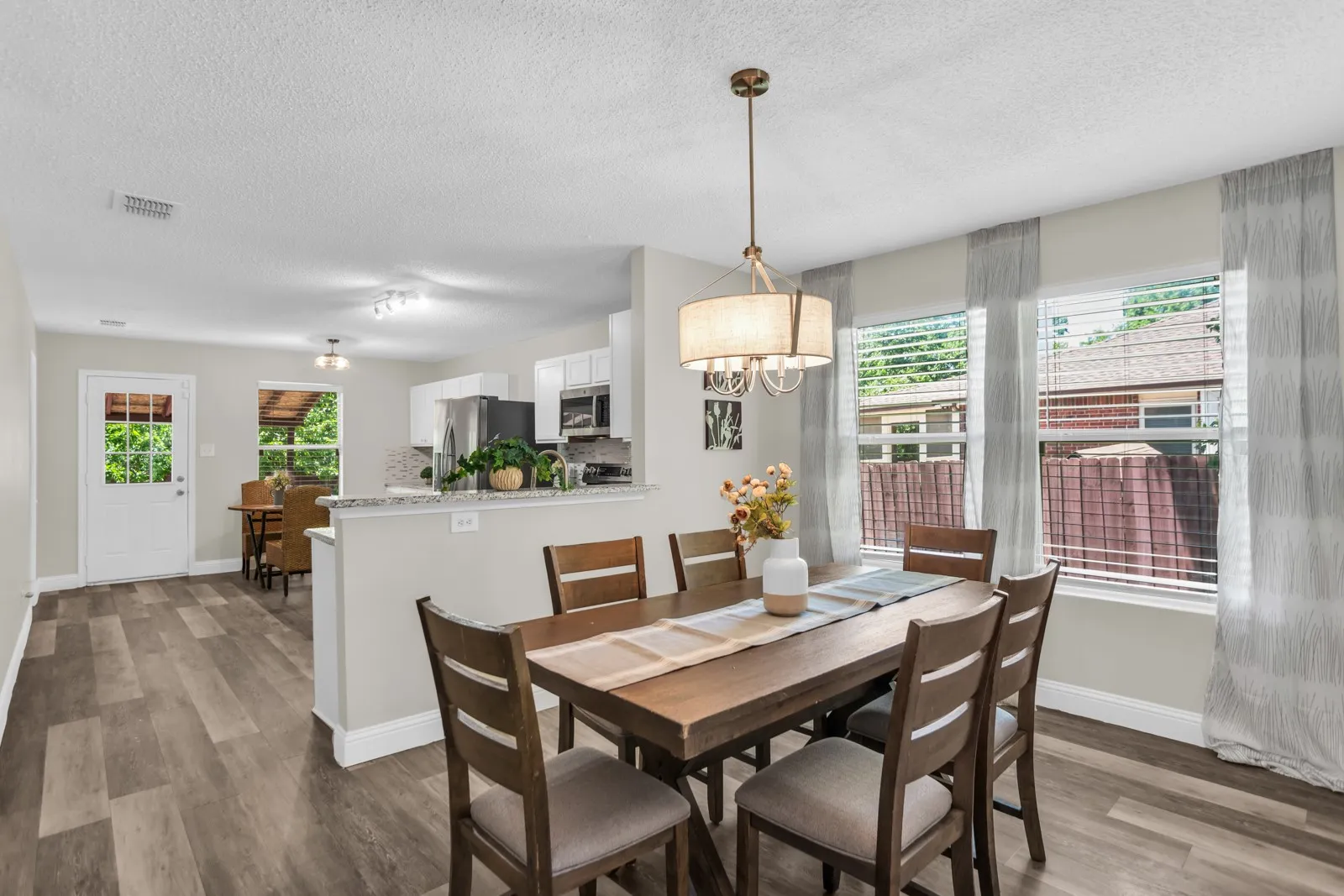 Dining area featuring wood-finish flooring, a drum pendant light, and multiple windows