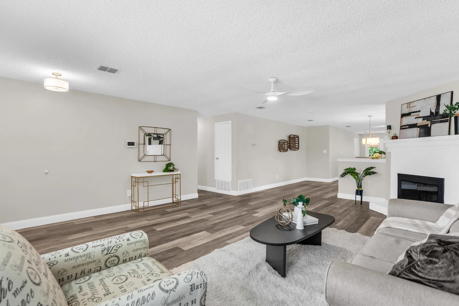 Spacious living area featuring wood-finish flooring, a built-in fireplace with a mantel, and a ceiling fan