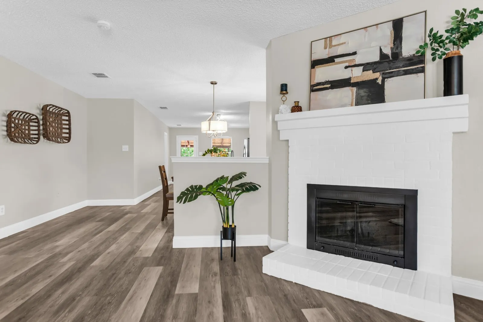 White brick fireplace with a substantial mantel, dark wood-finish flooring, light neutral wall paint, and a built-in half wall