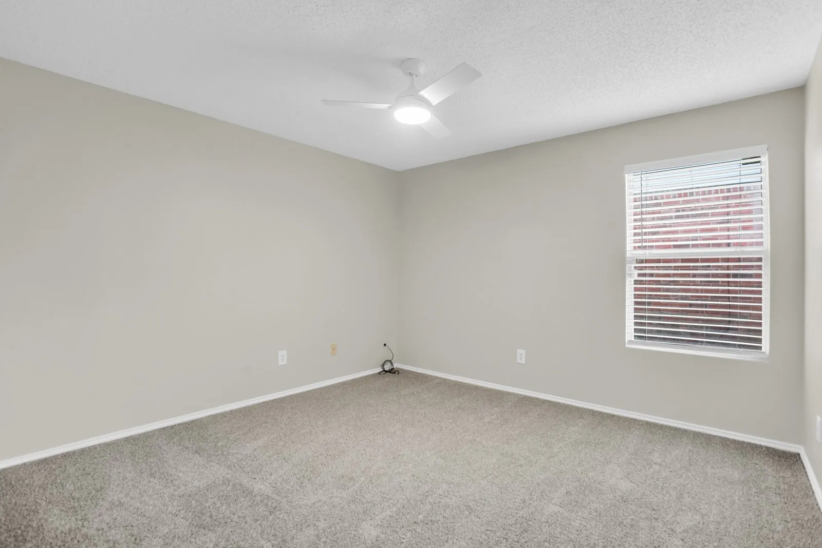 Carpeted flooring, neutral wall paint, ceiling fan with integrated lighting, and a window with horizontal blinds