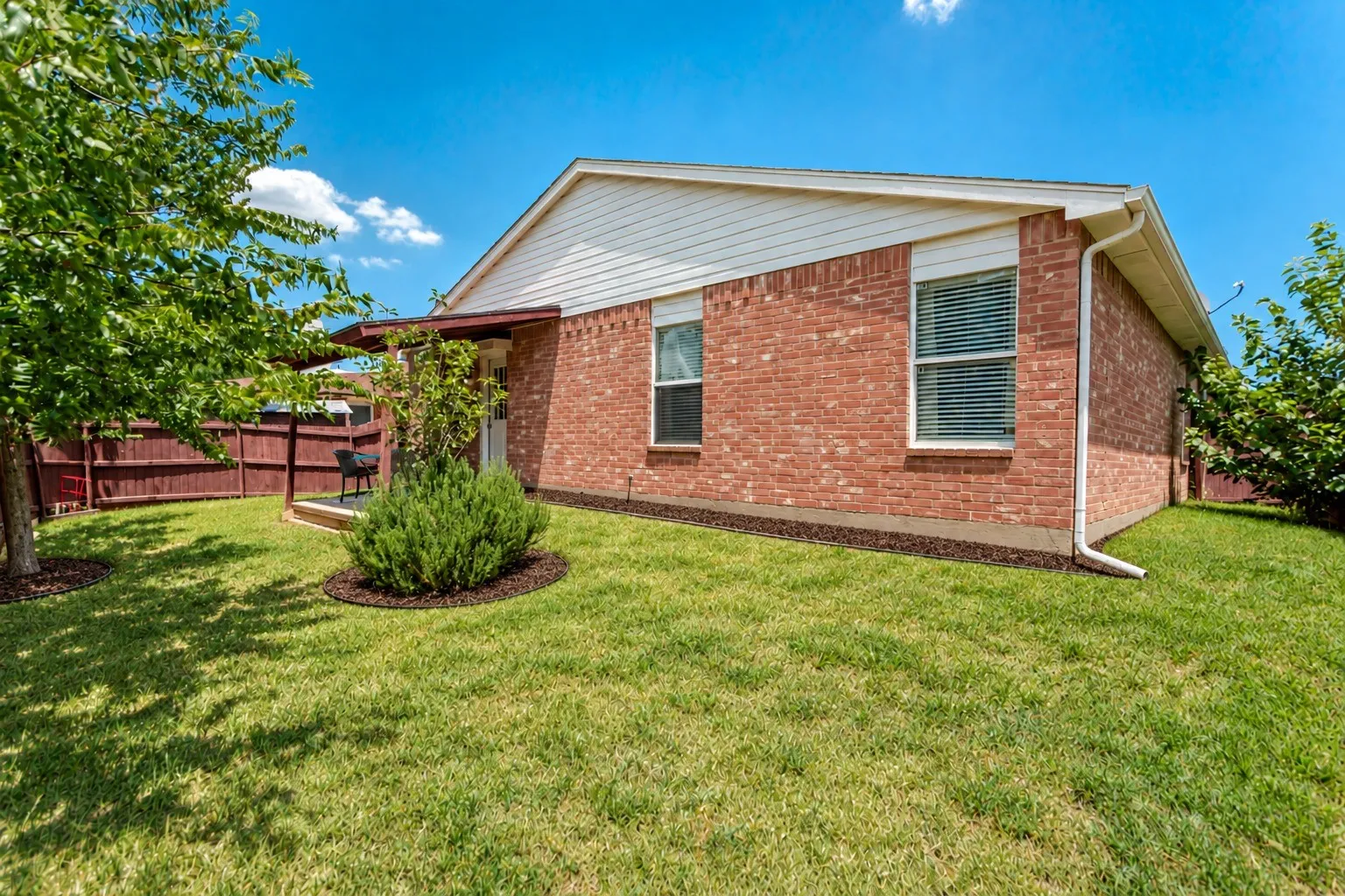 Brick exterior with white siding accents and a covered patio