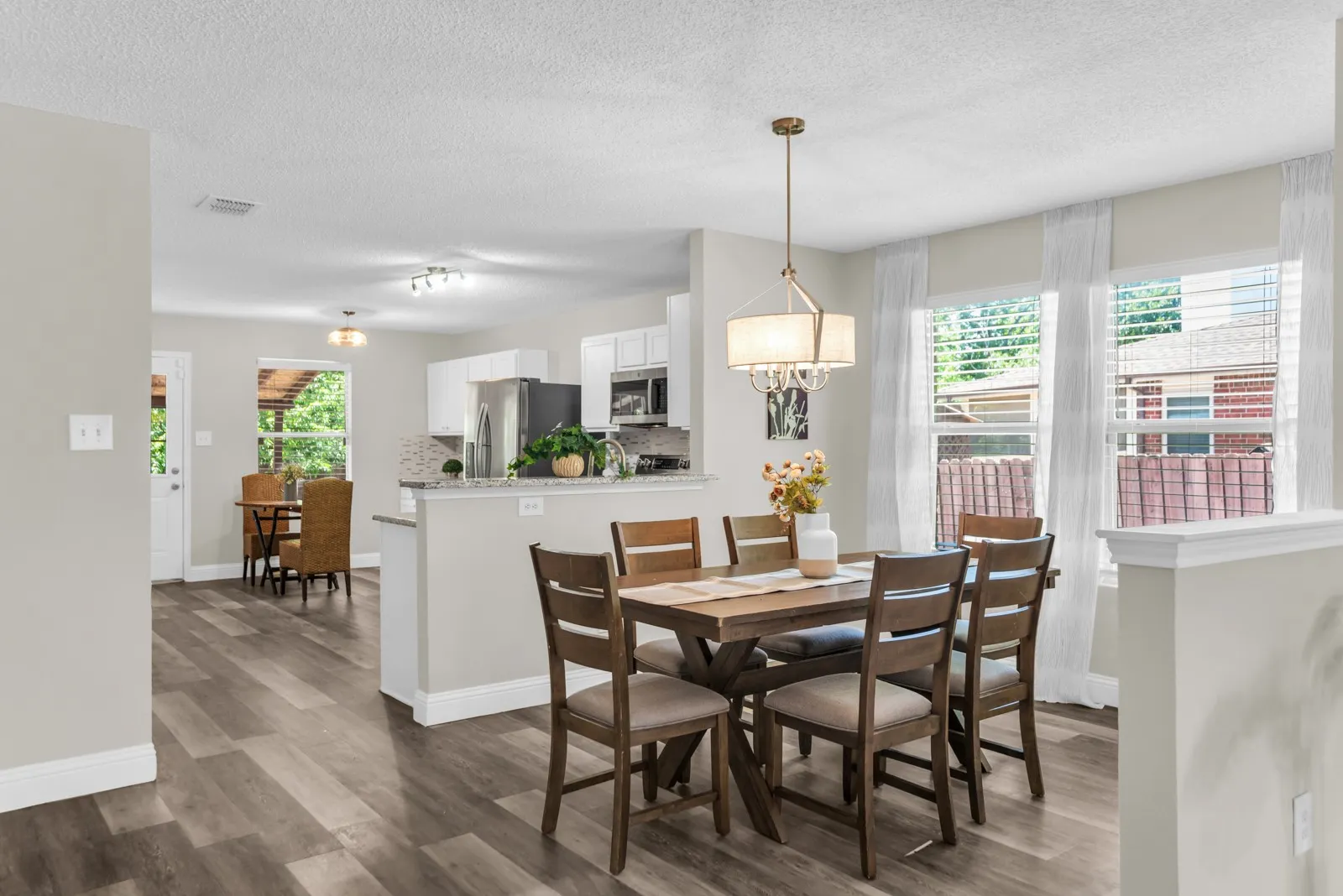 Open-concept dining area featuring wood-finish flooring and a contemporary chandelier