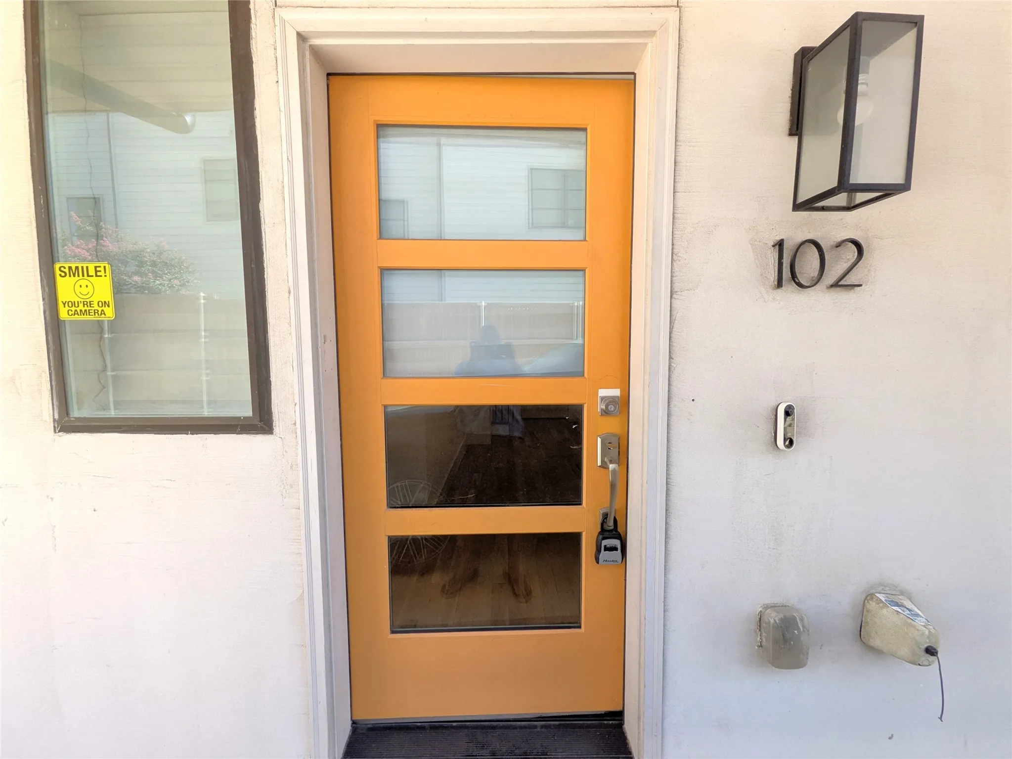 Modern entry door with multiple glass lites, a contemporary wall sconce, and distinct exterior numbering