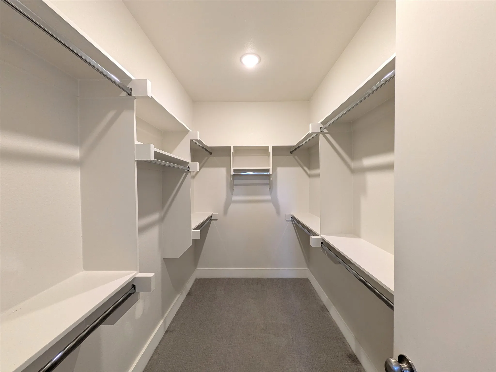 Walk-in closet with extensive built-in shelving, multiple hanging rods, and recessed ceiling lighting
