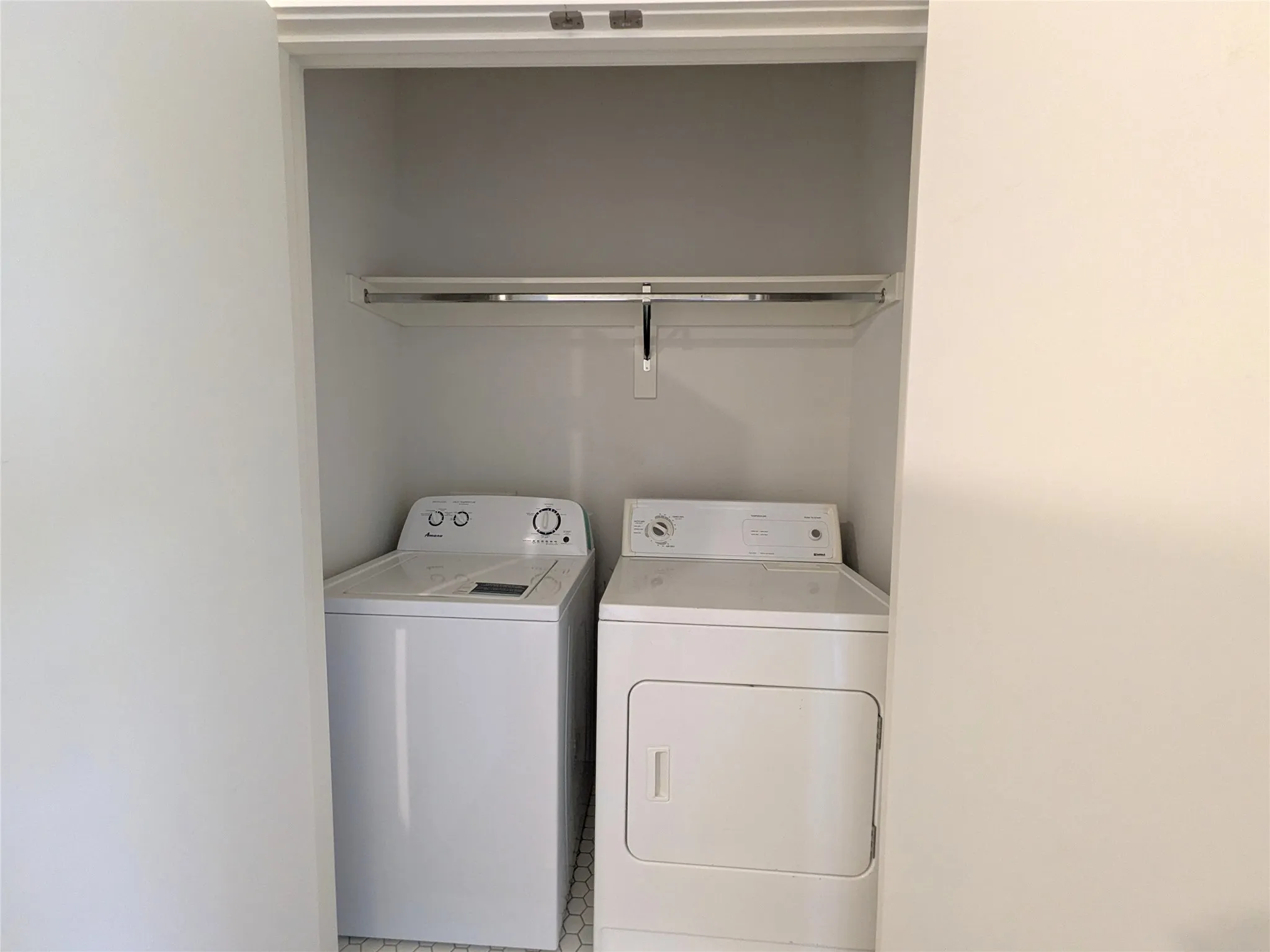 Dedicated laundry closet featuring a top-load washing machine and a front-load dryer
