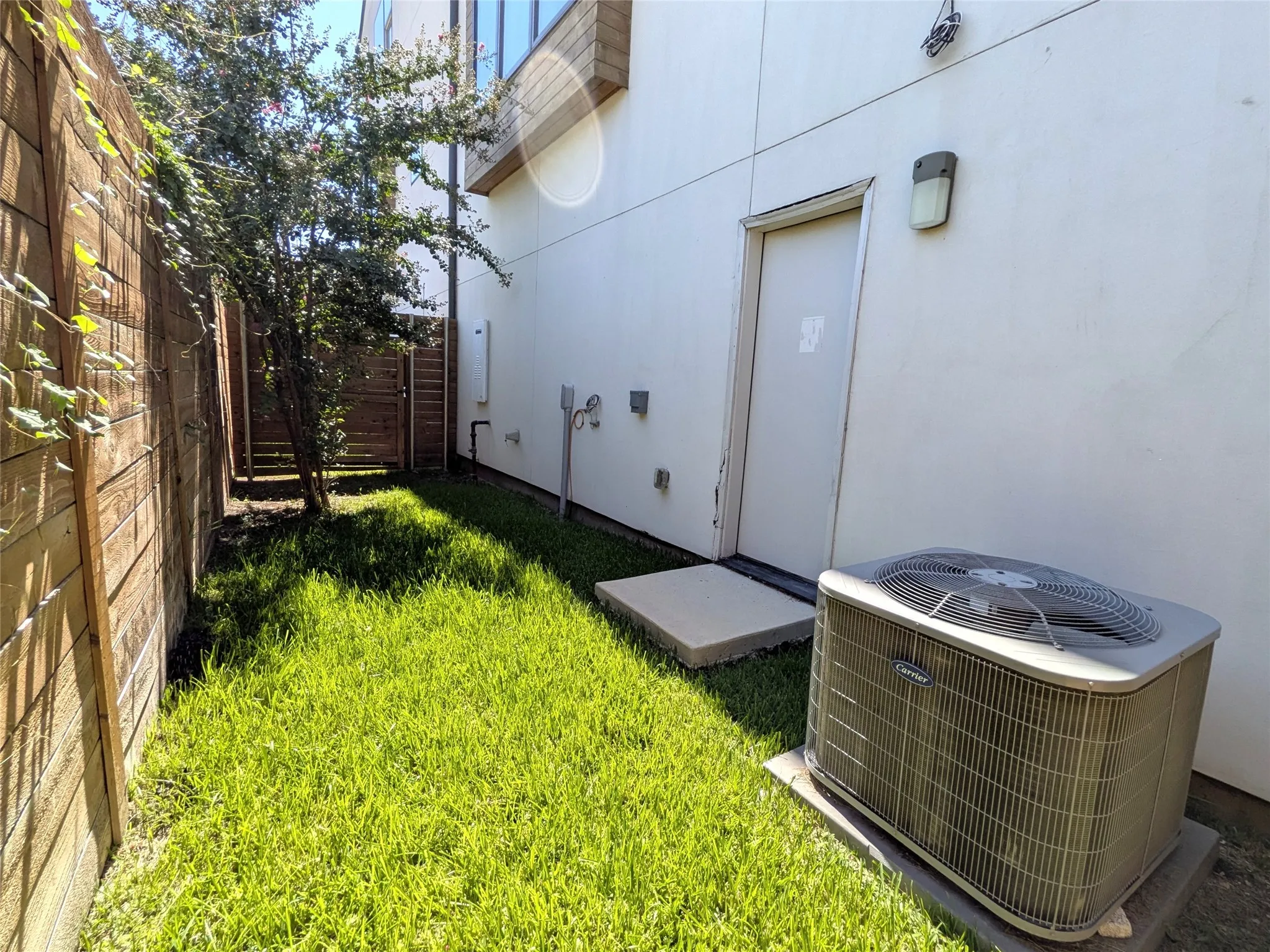 Private fenced outdoor area featuring a mature tree and a compact lawn