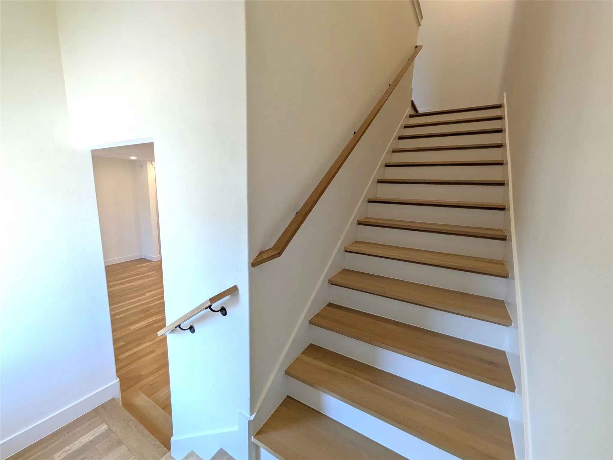 Wood-finish staircase with white risers and natural wood handrails