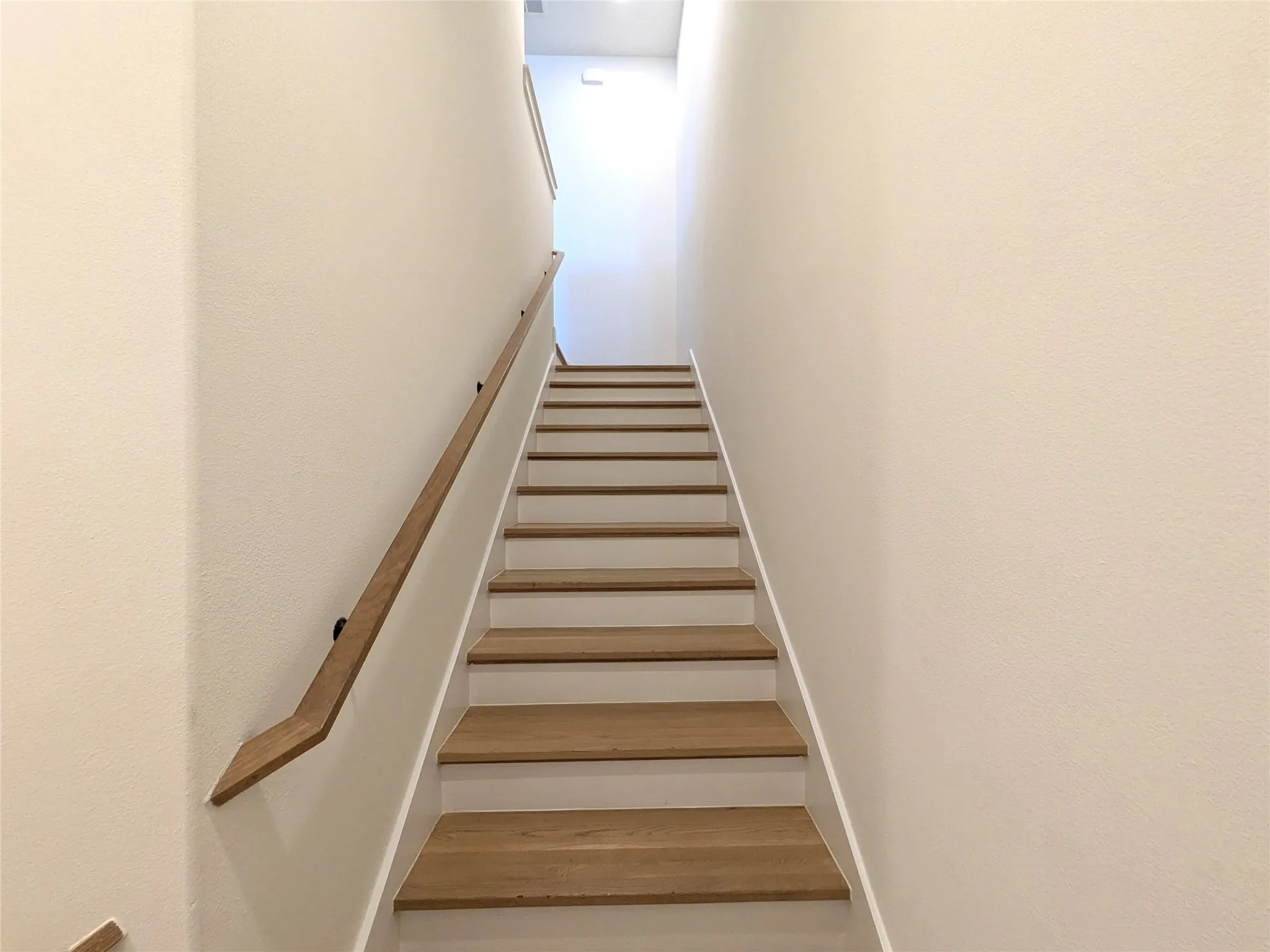 Staircase featuring wood-finish treads and a contemporary wood handrail