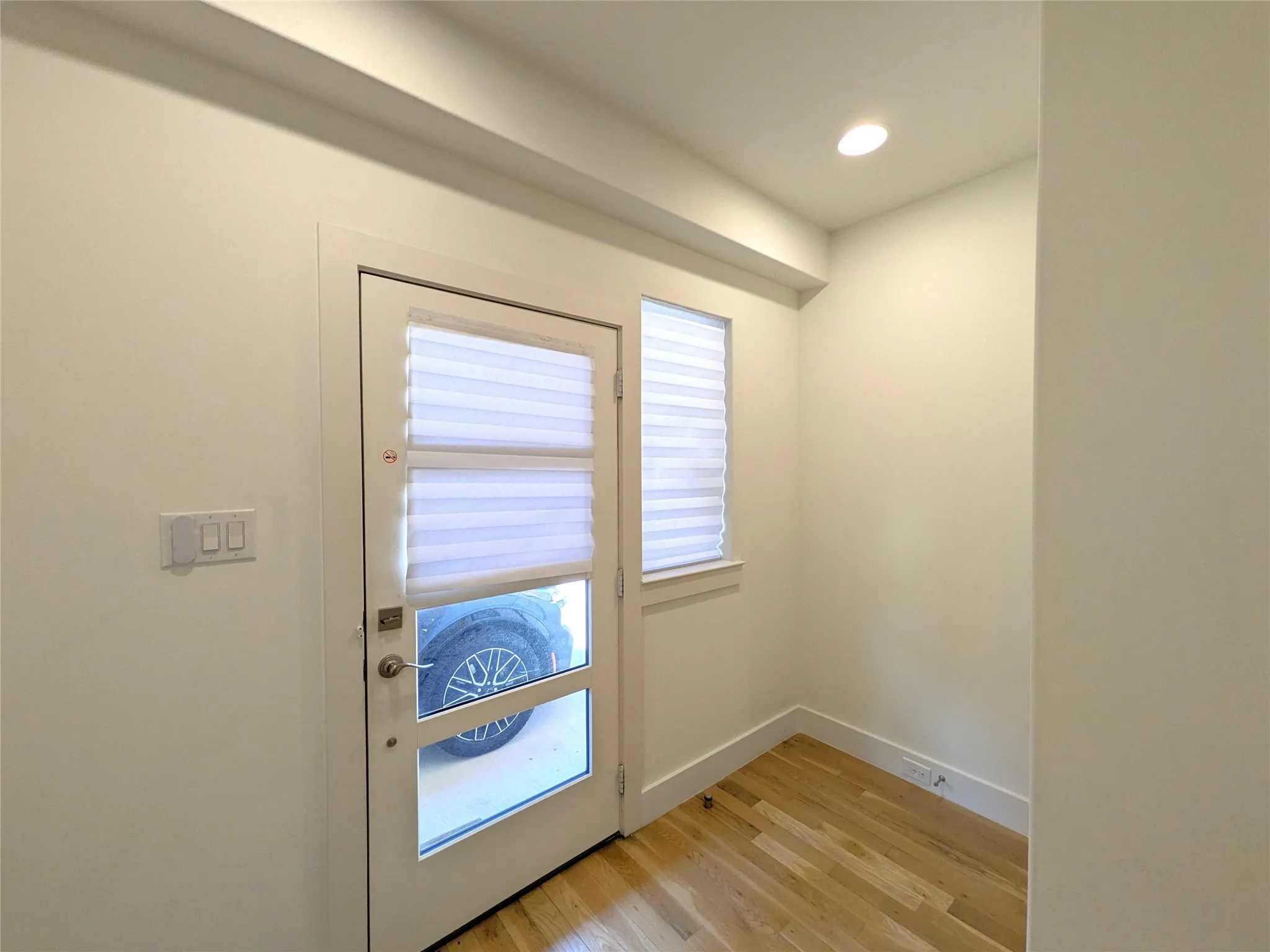 Recessed ceiling lighting, wood-finish flooring, and a glass-paneled door with integrated blinds
