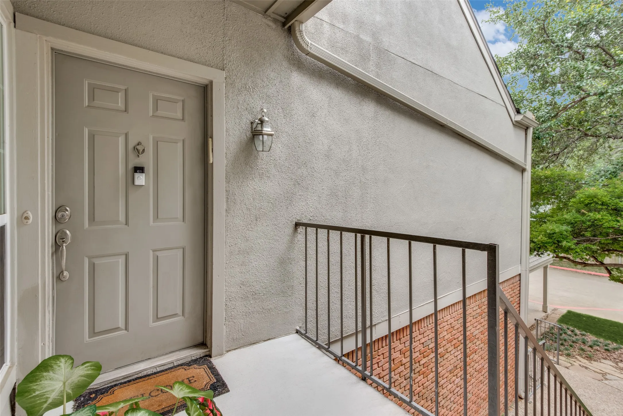 Panel-style door with a doorbell feature, complemented by a wall-mounted exterior light fixture