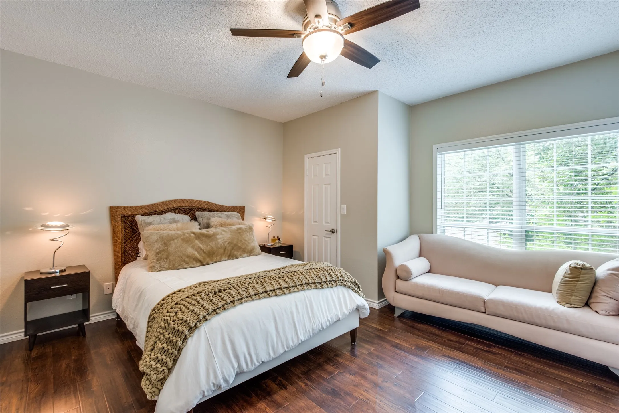 Wood-finish flooring, ceiling fan with integrated lighting, large window with blinds, and light-toned wall paint