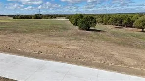 Expansive undeveloped lot featuring a concrete surface and distant trees