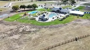 Community clubhouse featuring a swimming pool, shaded lounge areas, and adjacent green spaces
