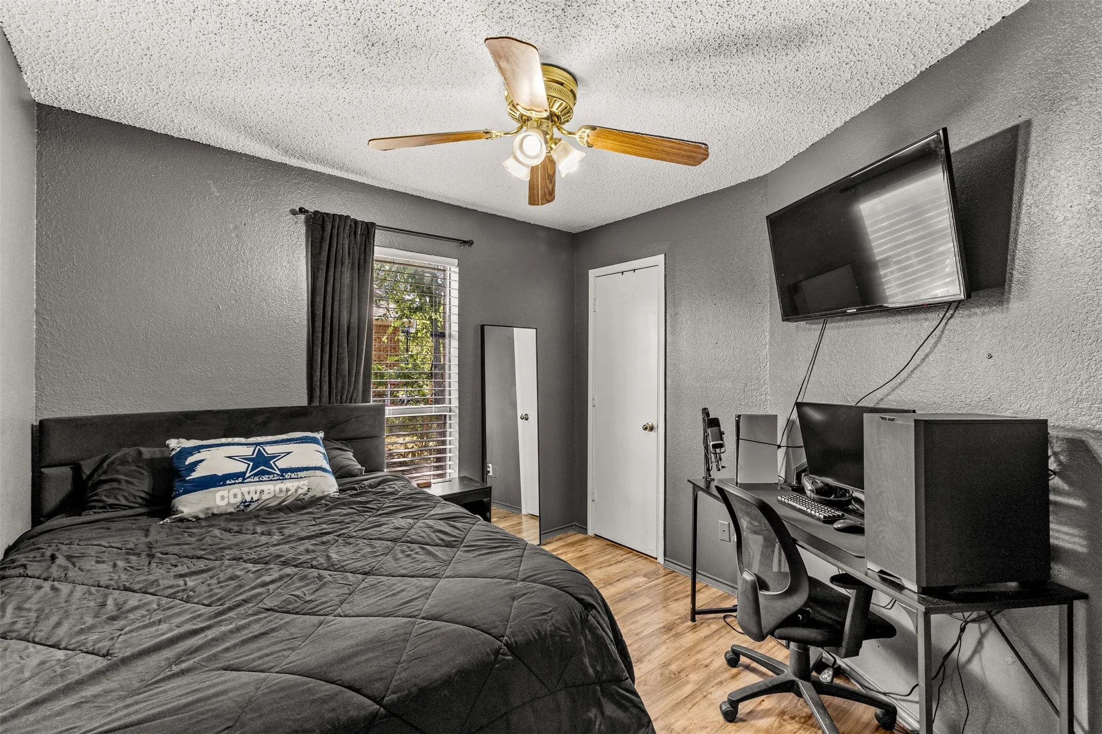 Wood-finish flooring with dark gray walls and a ceiling fan with light fixture