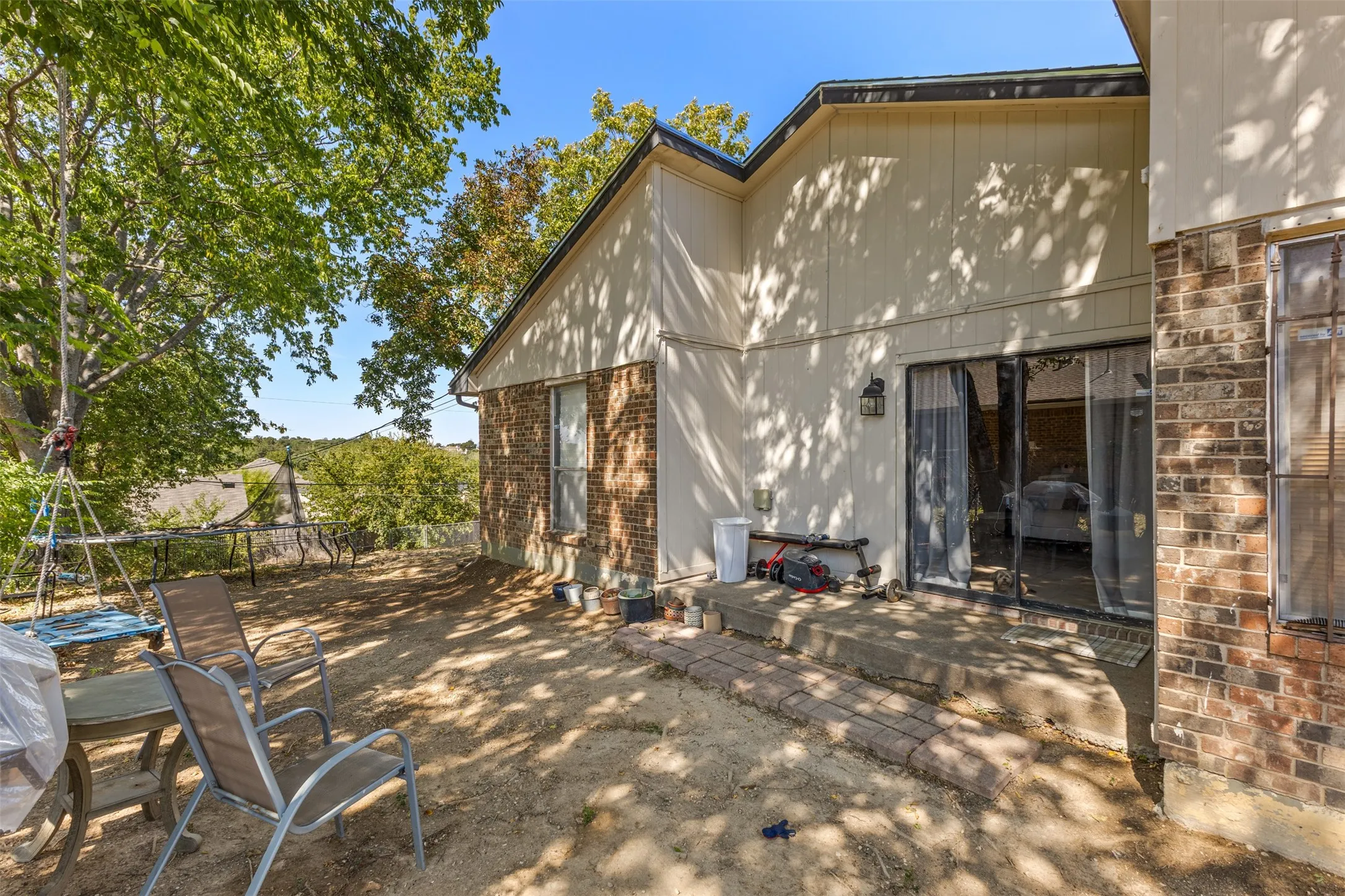 Rear exterior featuring brick and horizontal siding, a patio with concrete flooring, and sliding glass doors