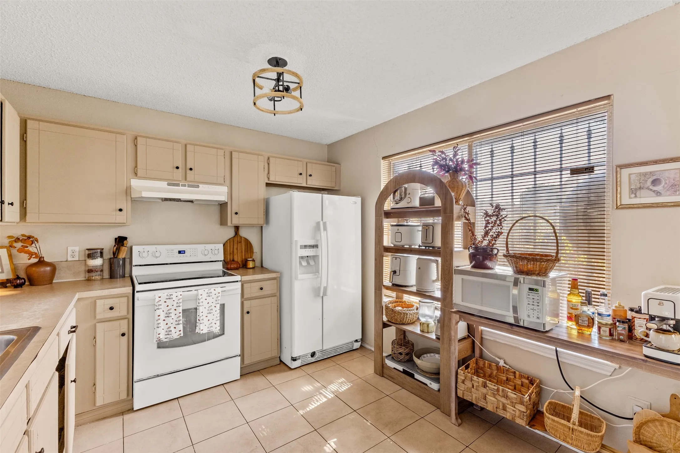 Kitchen featuring ceiling-mounted light fixture, tile flooring, and a large window