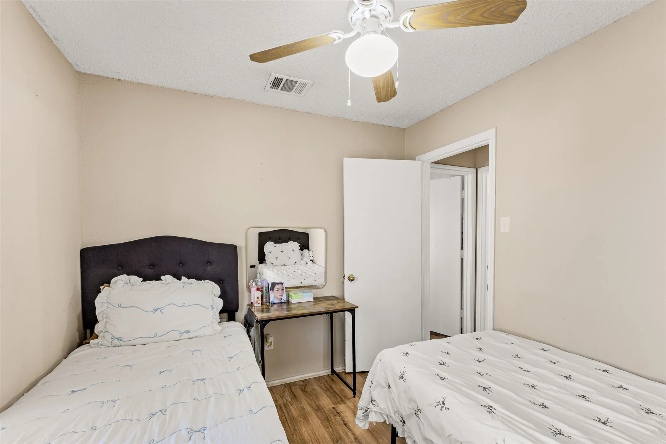 Wood-finish flooring, neutral wall paint, and a ceiling fan with integrated lighting