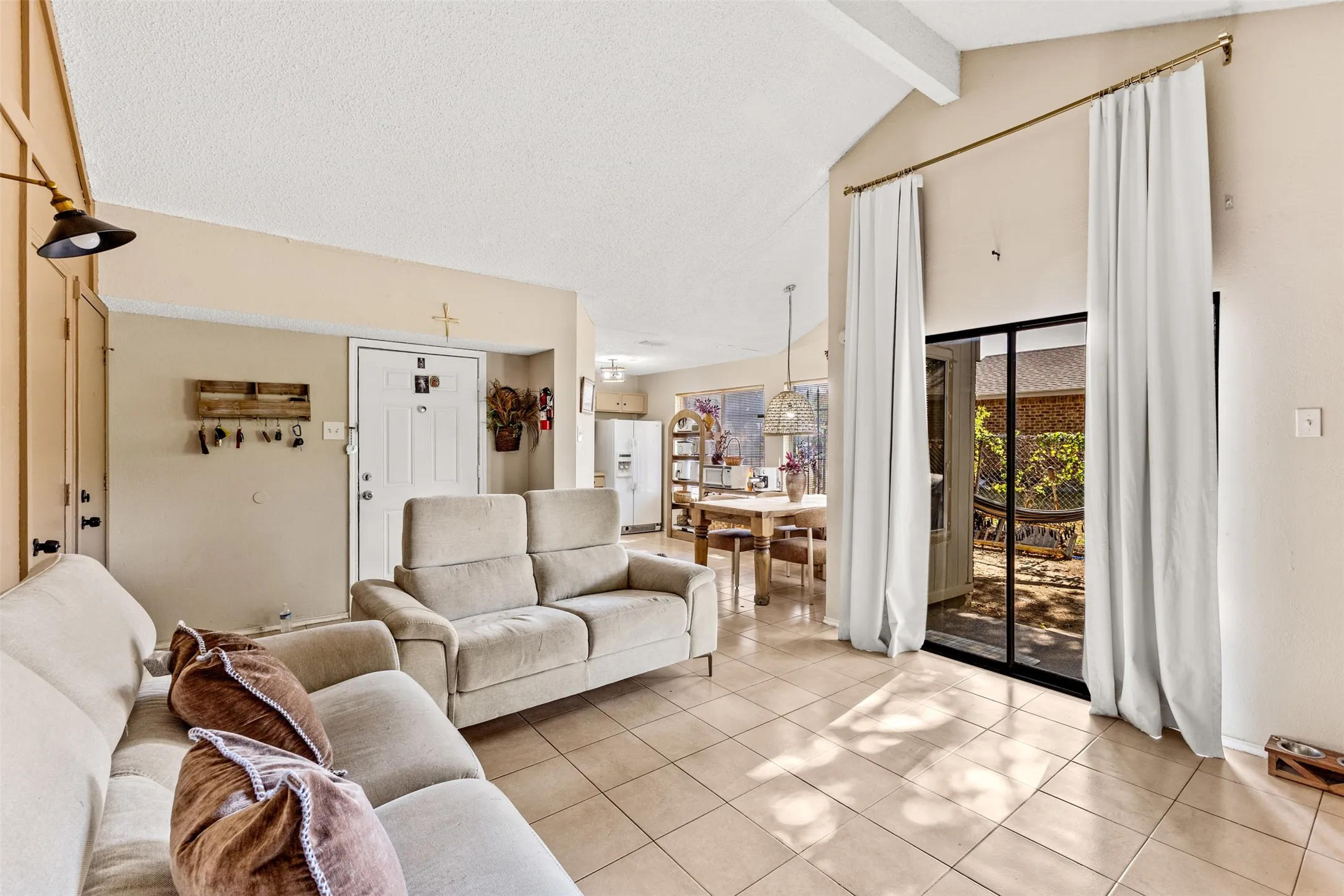 Vaulted ceiling, tiled flooring, expansive sliding glass door, white door, and an open layout