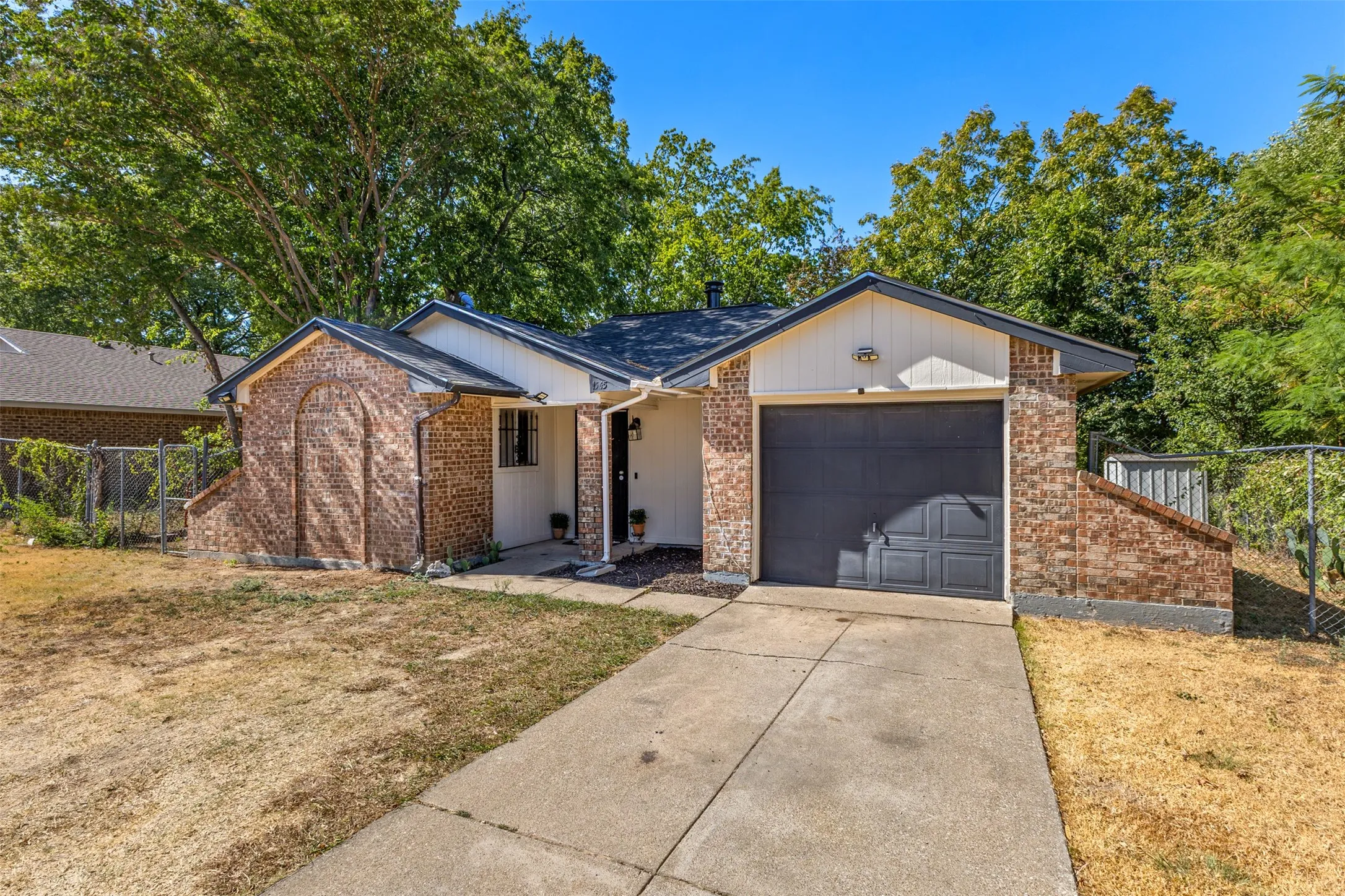 Brick exterior with white siding accents, an attached garage, and a concrete driveway