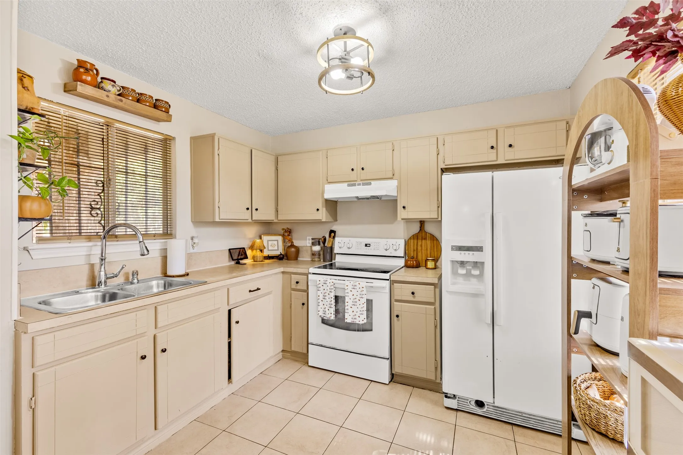 Kitchen featuring neutral cabinetry, a double basin stainless steel sink, and light-toned tile flooring