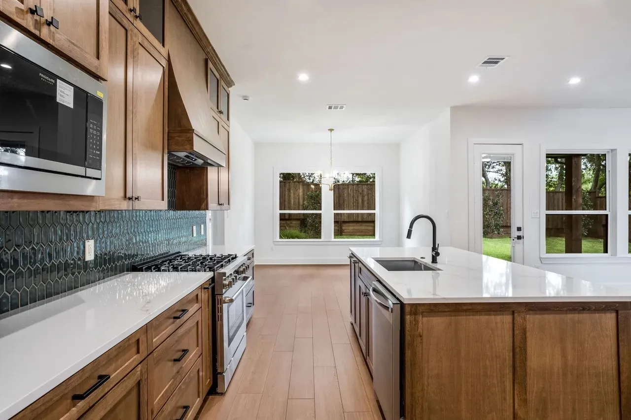 Gourmet kitchen featuring wood-finish cabinetry, white countertops, a dark-tiled backsplash, and stainless steel appliances