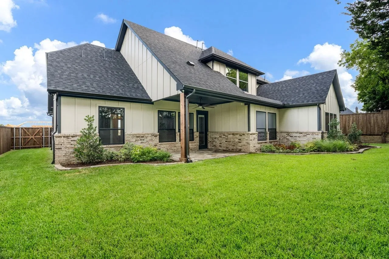 Expansive rear yard with a covered patio featuring a ceiling fan